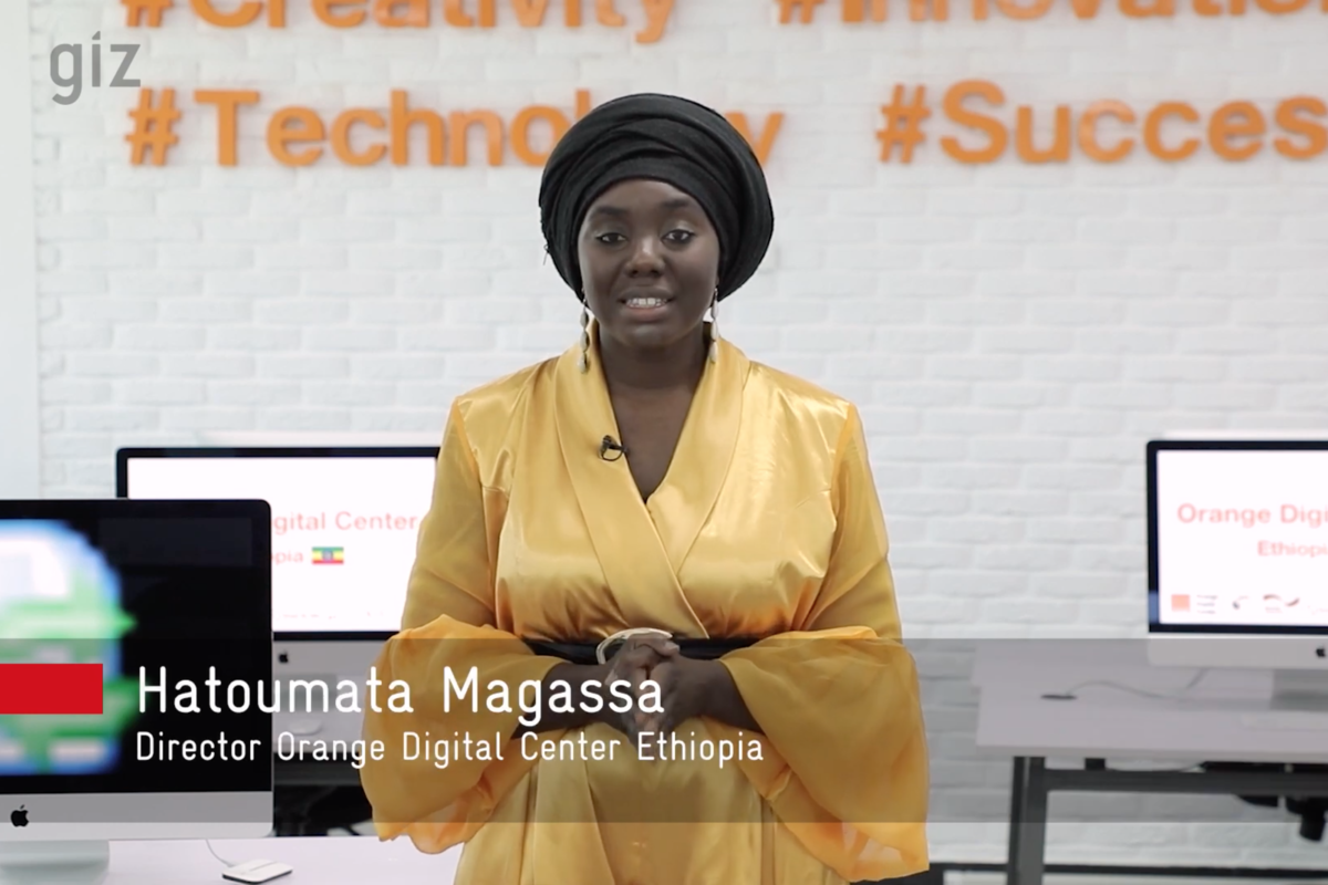 Foto: Hatoumata Magassa steht vor Tischen mit eingeschalteten Computerbildschirmen.