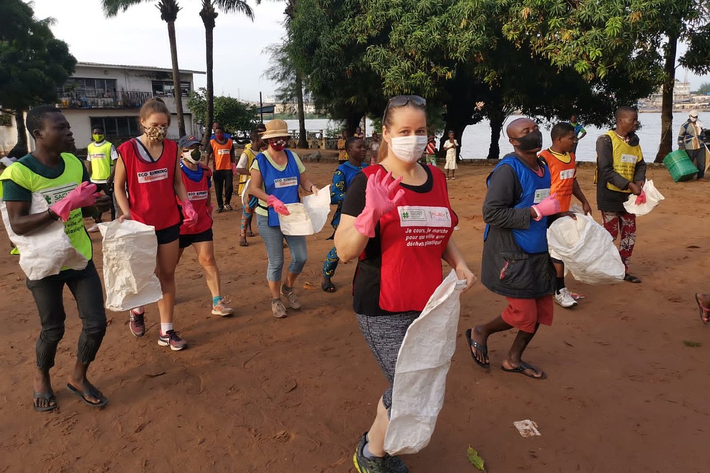 Foto: Eine große Gruppe von Personen, die in Reihen neben- und hintereinander stehen. Alle tragen Mund-Nase-Bedeckungen. Auf dem Boden jeweils ein leerer Müllsack.