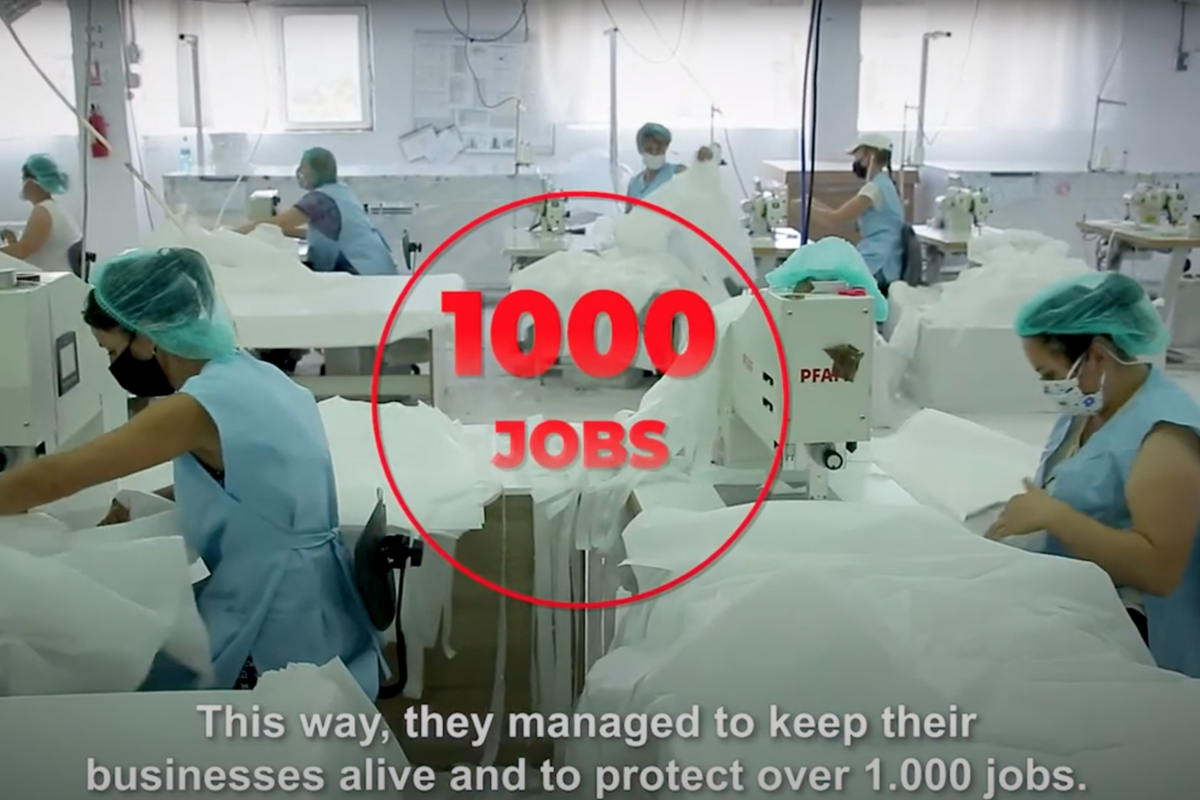 Foto: In einem Raum nähen Frauen an Industrienähmaschinen weißes Gewebe.