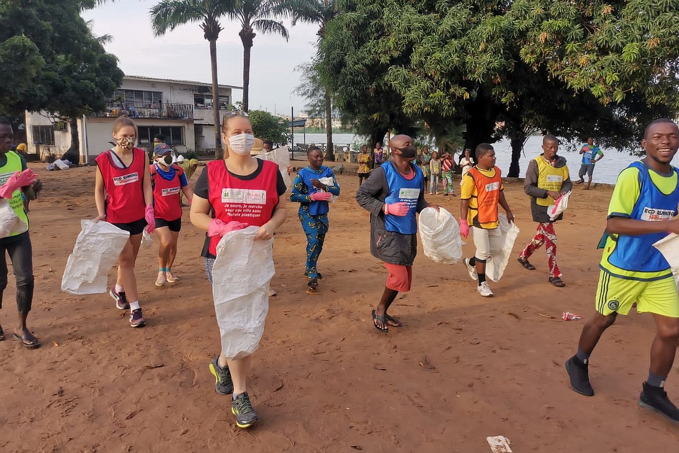 Foto: Mehrere Personen halten weiße, leere Plastiksäcke in den Händen. Einige tragen medizinische Masken.