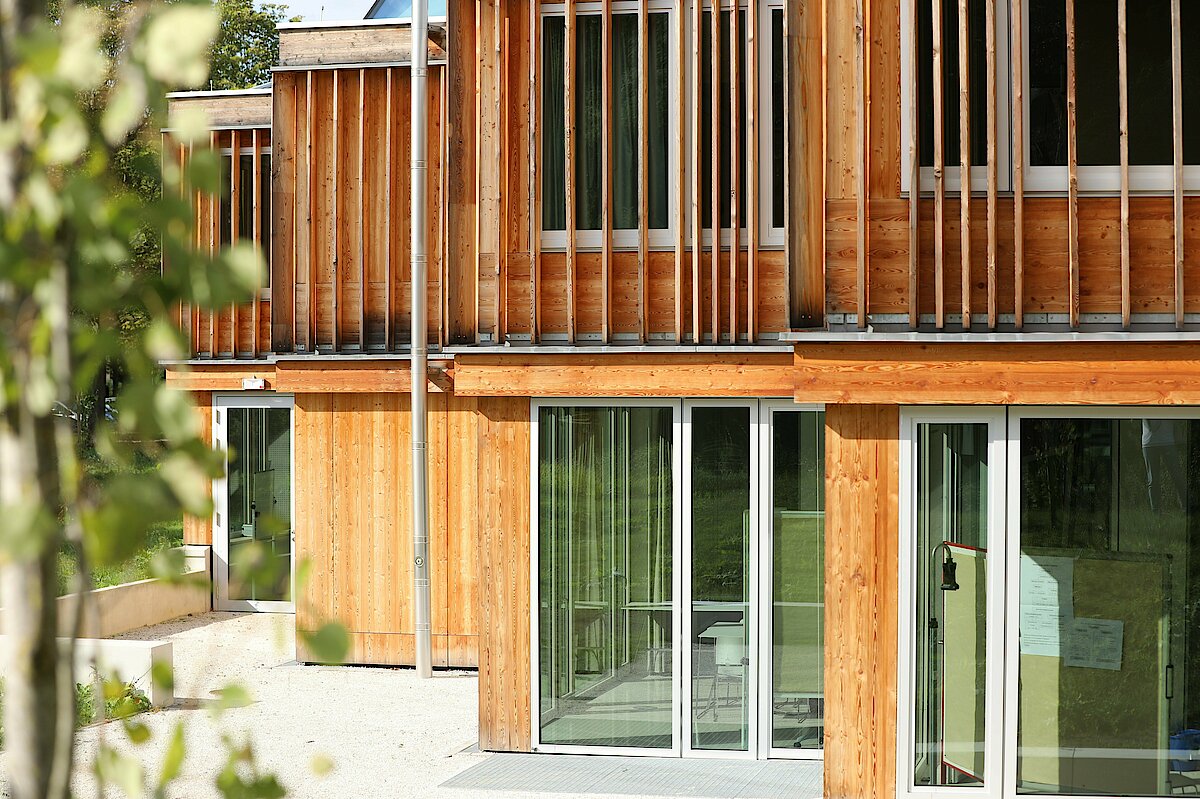 Foto: Fensterfront eines mit Holz verkleideten Gebäudes.