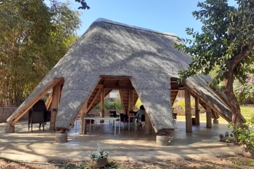 Foto: Versammlungsraum der GIZ in Malawi: offene Holzkonstruktion mit Grasdach