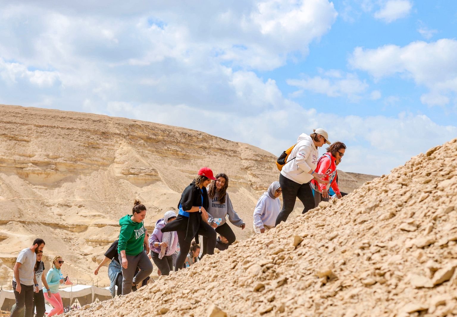 Foto: Mehrere Personen laufen einen steinigen Berg nach oben.