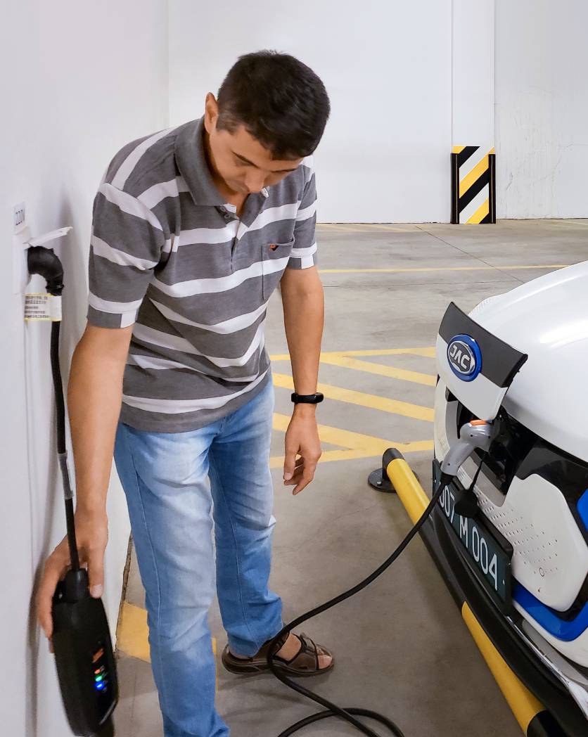 Foto: Ein Mann schaut auf das Ladegerät, an dem ein Elektroauto angeschlossen ist.