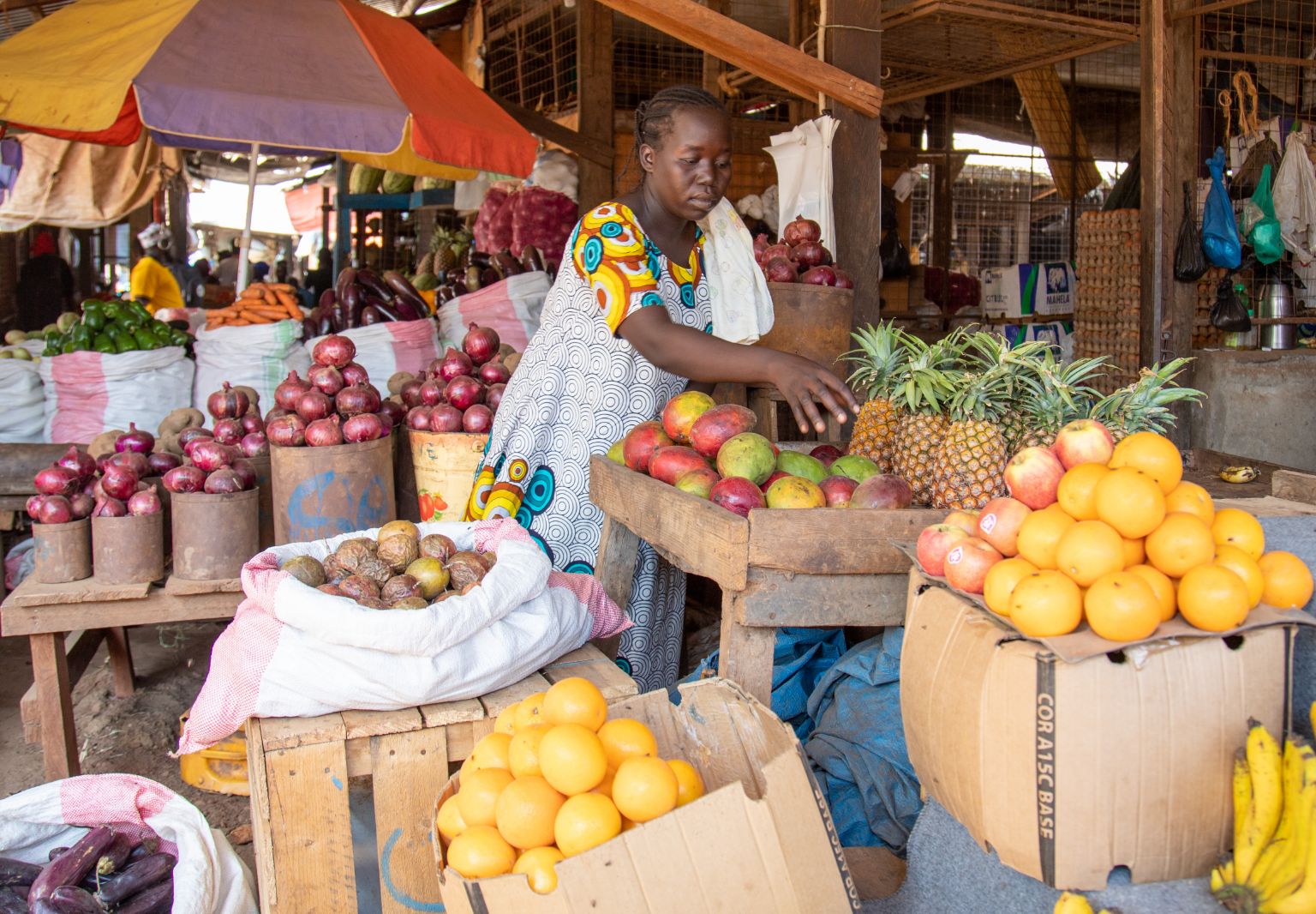Foto: Eine Frau kauft tropische Früchte an einem Markstand ein.