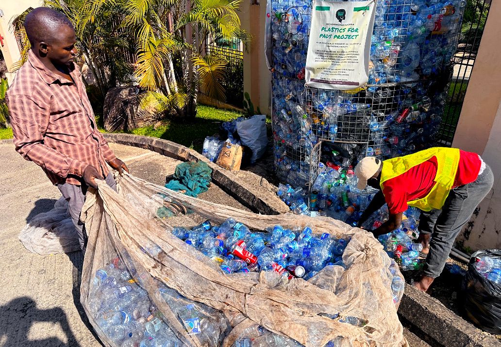 Foto: Zwei Männer leeren einen Container mit Plastikpfandflaschen.