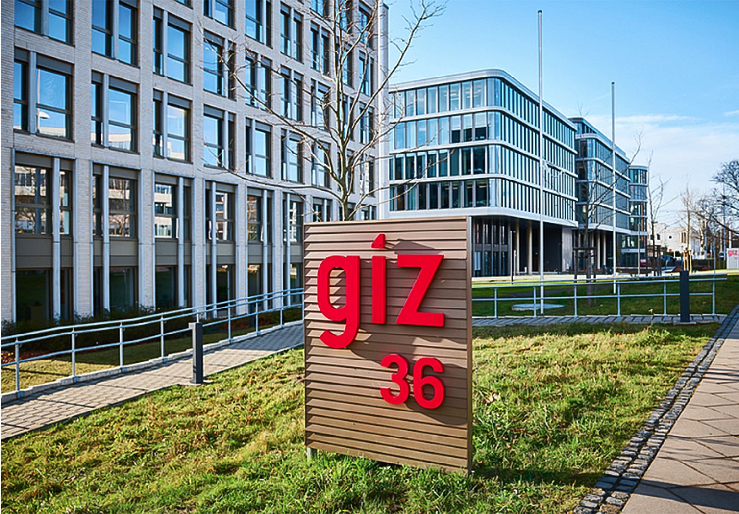 Foto: Vor mehreren modernen Gebäuden steht ein Schild mit dem GIZ-Logo.