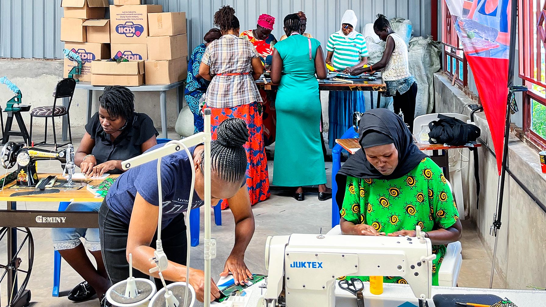 Eine Gruppe Frauen in einer Fabrikhalle übt den Umgang mit Recycling-Materialien und näht daraus Produkte.